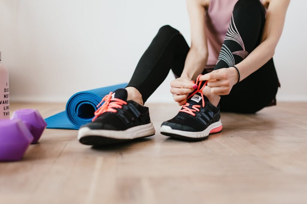 pexels-photo-4498553 Anonymous slender female athlete tying shoelaces near sport accessories