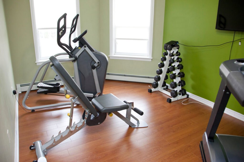 Efficient Home Gym Layout for Small Spaces Compact home gym setup with elliptical, weight bench, and dumbbell rack in a small room.