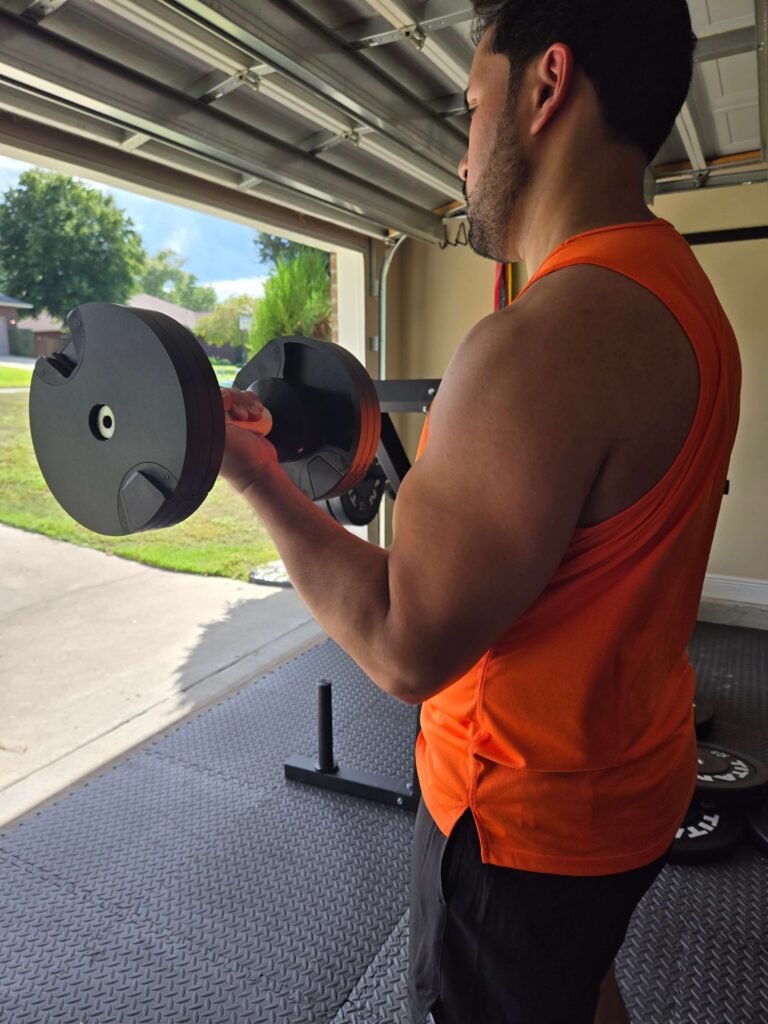 home-gym-bicep-curl-dumbbell Person performing a bicep curl with a dumbbell in a home gym setup.