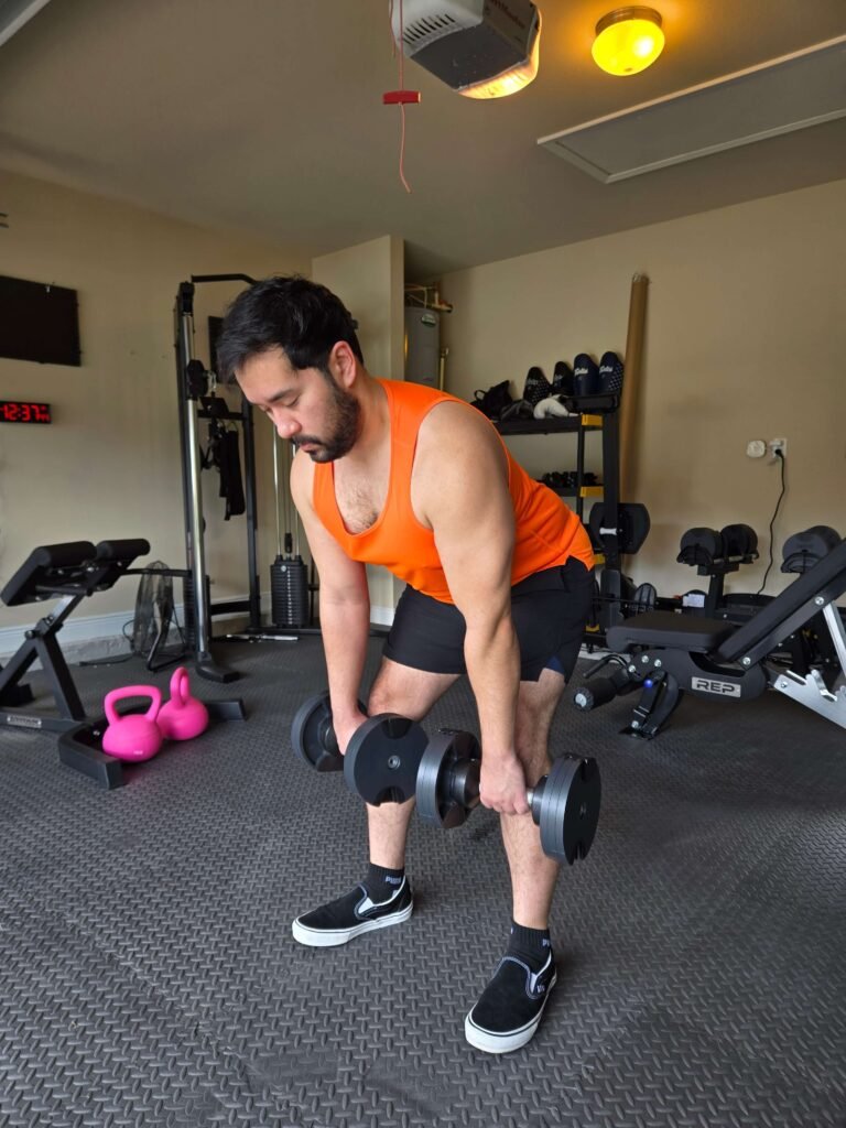 Dumbbell Deadlift in Garage Home Gym for Glute Strength A man performing a dumbbell deadlift in a garage home gym.
