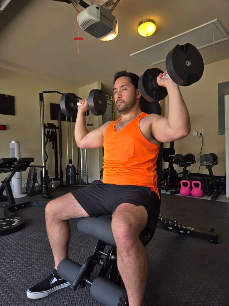 Seated Dumbbell Shoulder Press in Garage Home Gym for Shoulder Strength Person performing a seated dumbbell shoulder press in a garage home gym.