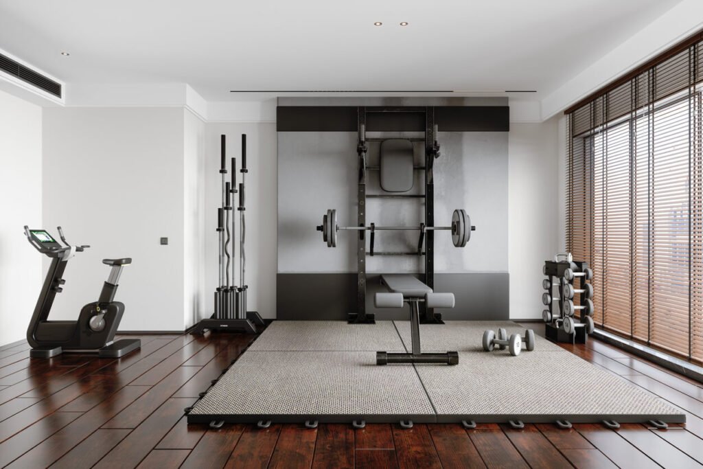 Home gym setup with a stationary bike, dumbbell rack, and barbell rack for strength and cardio workouts.