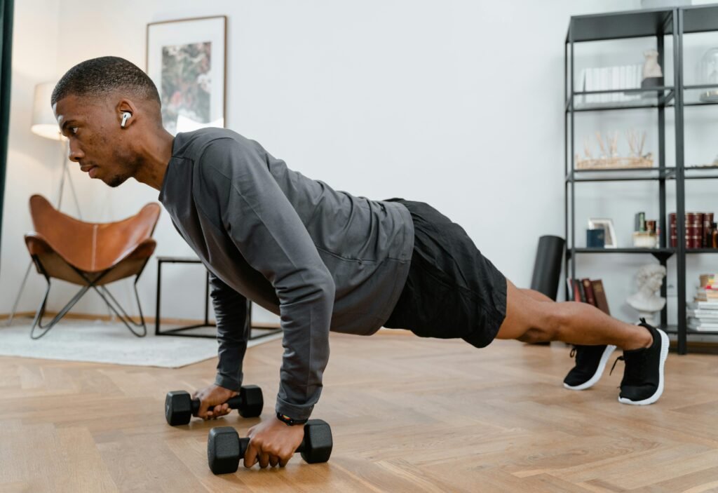 Push-Up Hold with Dumbbells During Bodyweight Workout at Home Man performing a push-up hold using dumbbells during a home bodyweight workout