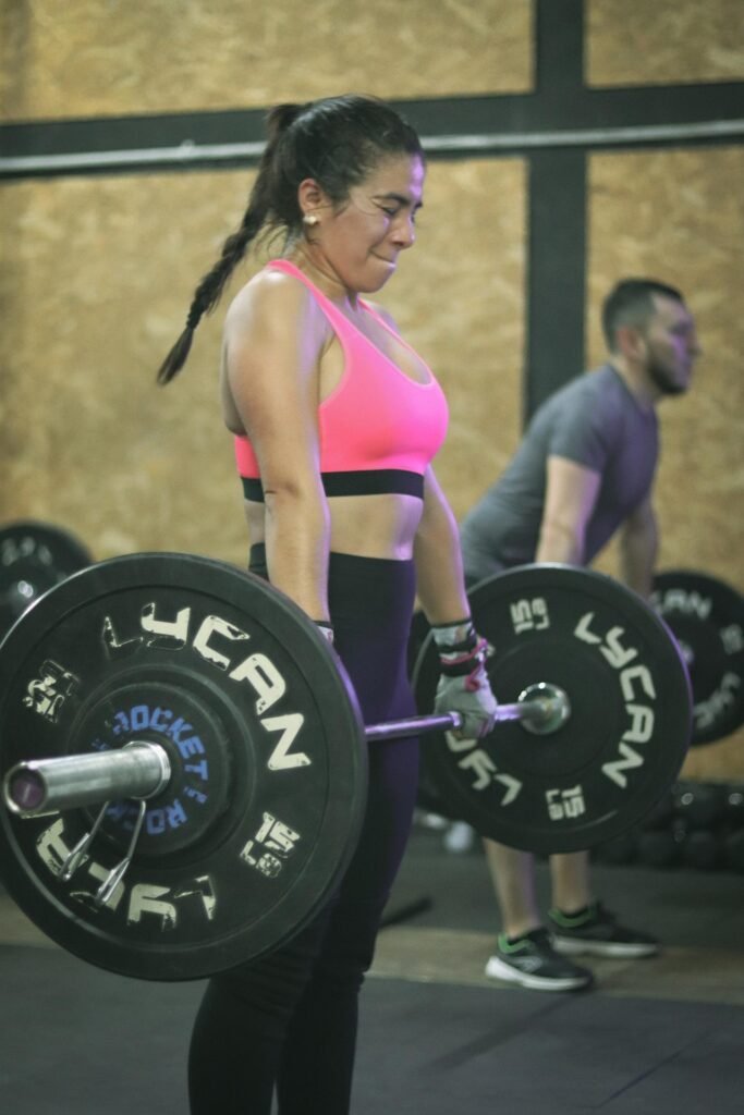 Woman Performing Barbell Deadlift for Hypertrophy Training Woman doing a barbell deadlift in the gym to build muscle through hypertrophy training